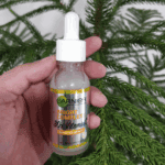 Garnier Bright Complete 30x Vitamin C Booster Serum bottle held in hand in front of green leaves, 30ml.