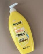 Garnier Bright Complete Vitamin C Body Serum Lotion yellow bottle, 400ml, placed on a beige background