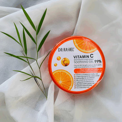 Dr Rashel Vitamin C Soothing Gel 99% in orange round container placed on white fabric with green plant, brightening and anti-aging skincare product.