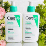 Two bottles of CeraVe Foaming Cleanser 236ml for normal to oily skin, fragrance-free face wash with ceramides, niacinamide, and hyaluronic acid, placed with flowers and greenery background.