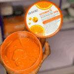 Open container of Dr Rashel Vitamin C Soothing Gel 99% with bright orange gel texture, held in hand, anti-aging and brightening skincare product.