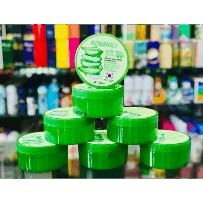 Stack of Roushun Aloe Vera Soothing & Moisturizing Gel tubs (300ml) arranged in a pyramid display inside a store. Bright green packaging with aloe vera leaf design, highlighting benefits like moisturizing, oil control for acne, after-sun repair, and soothing care.