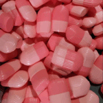 Multiple pink capsule-shaped ice roller molds stacked together.