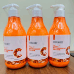 Three bottles of Dr Rashel Vitamin C Brightening & Nourishing Body Lotion 300ml standing together on a wooden table.