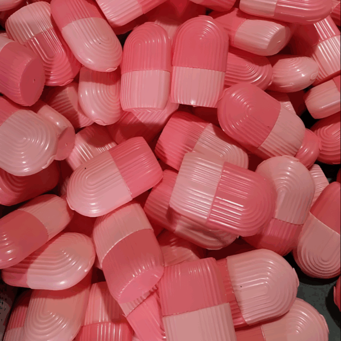 Multiple pink capsule-shaped ice roller molds stacked together.