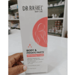 Hand holding a Dr Rashel Body & Private Parts Whitening Cream box in a store setting, with shelves of skincare products in the background.