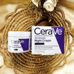 CeraVe Skin Renewing Night Cream jar and box placed on a woven decorative mat with cream-colored flowers in the background.