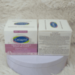 Two boxes of Cetaphil Healthy Radiance Brightening Cream 50g displayed side by side on a soft fabric surface, showing the front and back labels with niacinamide and Sea Daffodil formula details.