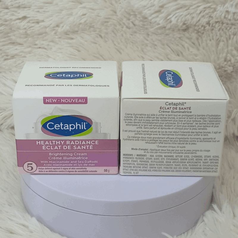 Two boxes of Cetaphil Healthy Radiance Brightening Cream 50g displayed side by side on a soft fabric surface, showing the front and back labels with niacinamide and Sea Daffodil formula details.