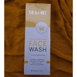 Dr Rashel Vitamin C Brightening Face Wash box in white and yellow packaging placed on a mustard fabric background.