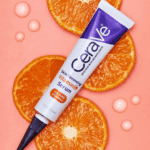 CeraVe Skin Renewing Vitamin C Serum tube placed on a pink background with fresh orange slices and serum drops. The image highlights its 10% Pure Vitamin C formula for bright, glowing, and healthy skin.