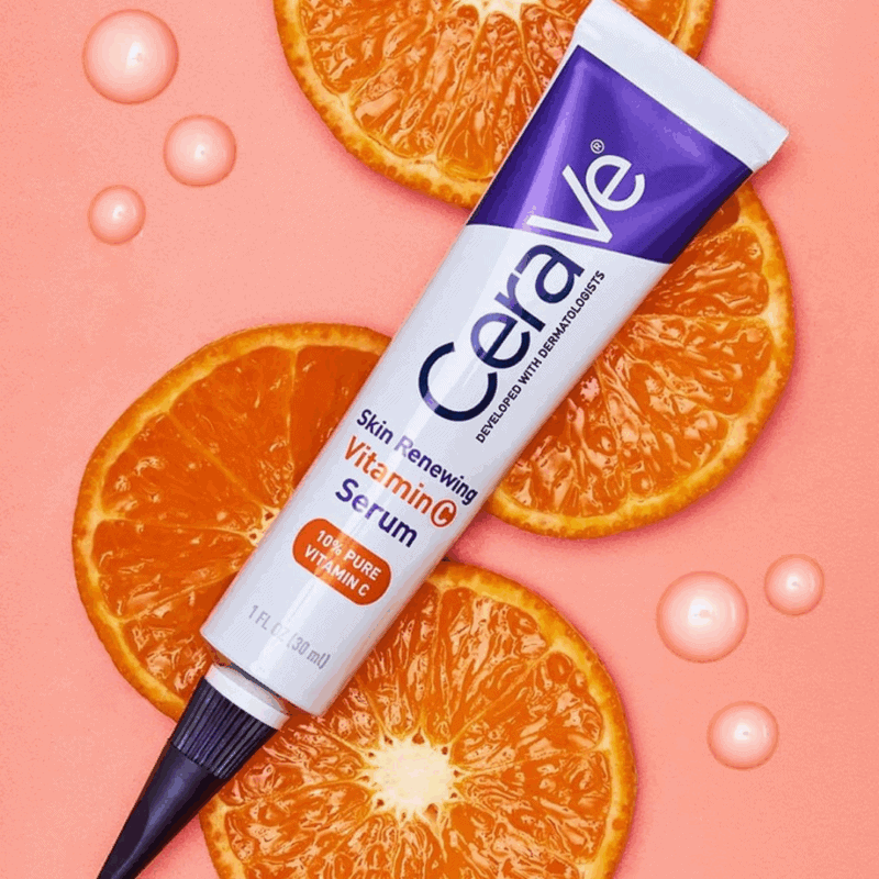 CeraVe Skin Renewing Vitamin C Serum tube placed on a pink background with fresh orange slices and serum drops. The image highlights its 10% Pure Vitamin C formula for bright, glowing, and healthy skin.