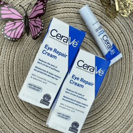 CeraVe Eye Repair Cream boxes and tube displayed on a textured surface with a butterfly decoration, highlighting its benefits for reducing puffiness, dark circles, and restoring moisture around the eyes.