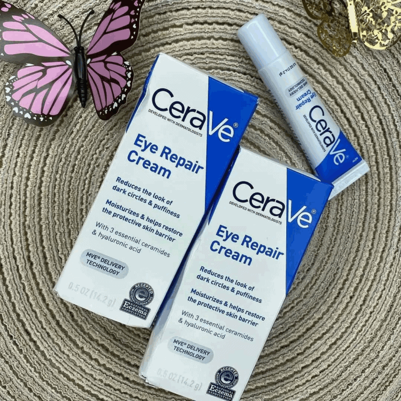 CeraVe Eye Repair Cream boxes and tube displayed on a textured surface with a butterfly decoration, highlighting its benefits for reducing puffiness, dark circles, and restoring moisture around the eyes.