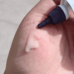 Close-up of CeraVe Skin Renewing Vitamin C Serum’s creamy pink texture on skin, with the serum’s tube applicator visible. The lightweight, fast-absorbing formula helps brighten and smooth the complexion.