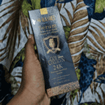 Dr. Rashel 24K Gold & Collagen Serum box held in hand, black-and-gold packaging labeled “With Real Gold Atoms & Collagen,” designed to support skin hydration, firmness, and a youthful glow.