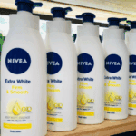 Multiple bottles of Nivea Extra White Firm & Smooth Body Lotion arranged on a shelf, showing the product’s Q10 and Vitamin C formula for firm, radiant, and smooth skin.