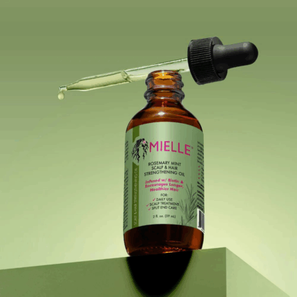 Open Mielle Rosemary Mint hair oil bottle with dropper showing lightweight oil texture against green background.