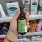 Hand holding Mielle Rosemary Mint scalp and hair strengthening oil inside a retail store shelf.