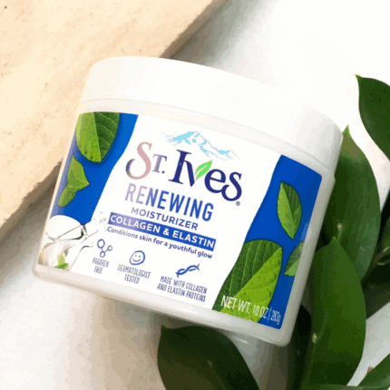 St. Ives Renewing Moisturizer Collagen & Elastin jar placed on a light surface with green leaves for a natural skincare look.