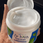 Open St. Ives Renewing Moisturizer jar revealing the smooth white cream texture inside.