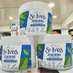 Three St. Ives Renewing Moisturizer Collagen & Elastin tubs stacked on a store counter with shelves in the background.