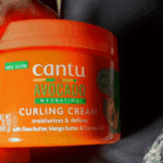 Real product image of Cantu Avocado Hydrating Curling Cream jar held in hand