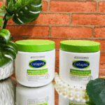 Two Cetaphil Moisturizing Cream jars for sensitive skin displayed on a glass surface