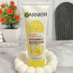 Garnier Bright Complete Vitamin C face wash placed on surface with decorative background