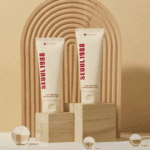 Two Seoul 1988 snail mucin rice cream tubes on wooden blocks with decorative background