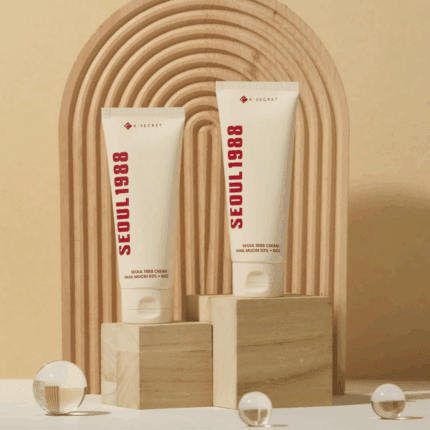 Two Seoul 1988 snail mucin rice cream tubes on wooden blocks with decorative background