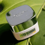 L’Oréal Glycolic Bright Glowing Day Cream SPF 17 jar placed on green leaf background