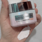 L’Oréal Glycolic Bright Glowing Day Cream SPF 17 jar with cream texture shown on hand