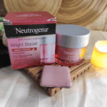 Neutrogena Bright Boost Night Cream jar displayed beside original box on wooden tray with candle and skincare setup