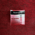 Neutrogena Bright Boost Night Cream box placed on red textured background showing product details