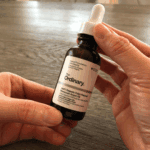Hand holding The Ordinary 100% Organic Cold-Pressed Moroccan Argan Oil dropper bottle