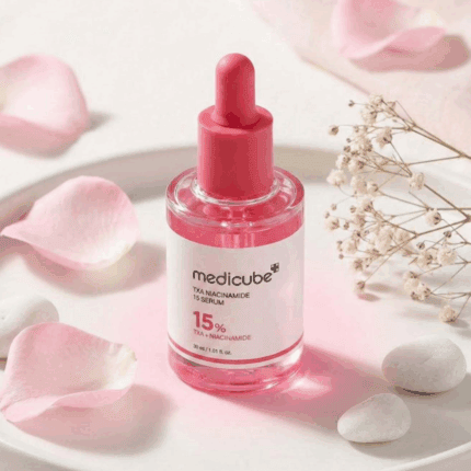 Medicube TXA Niacinamide 15 Serum displayed on a soft pink flat lay background