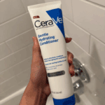 Hand holding CeraVe Gentle Hydration Conditioner 266ml in bathroom, gentle hydrating conditioner developed with dermatologists available in Sri Lanka