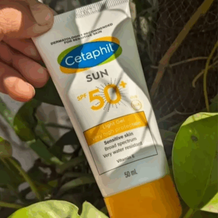 Hand holding Cetaphil Sun SPF 50+ Light Gel 50ml sunscreen tube outdoors among green leaves – lightweight, very high protection sunblock for sensitive skin in Sri Lanka