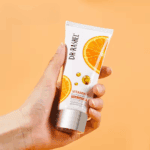 Hand holding Dr Rashel Vitamin C Brightening Anti Aging Facial Cleanser 80g tube with orange extract skincare product Sri Lanka