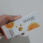 Hand holding Dr Rashel Vitamin C Private Part Whitening Cream box, side view packaging with orange vitamin C design, skincare product available in Sri Lanka