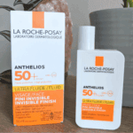 La Roche-Posay Anthelios SPF 50+ Ultra Fluid facial sunscreen bottle displayed beside its box on a wooden surface with houseplants in the background.