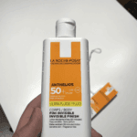 La Roche-Posay Anthelios Ultra Fluid SPF 50 125ml body sunscreen bottle held in hand, showing invisible finish formula with high UVA and UVB protection.