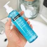 Close up hand holding Neutrogena Hydro Boost Water Gel Cleanser 200ml pump bottle on soft fabric background hydrating hyaluronic acid facial cleanser Sri Lanka