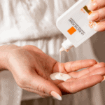 Close-up of sunscreen lotion being poured from a La Roche-Posay Anthelios SPF 50+ Ultra Fluid bottle into an open palm, showing the lightweight fluid texture.