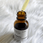 Close-up of The Ordinary Retinol 0.5% in Squalane serum bottle with glass dropper dispensing oil from amber glass bottle on soft white background.