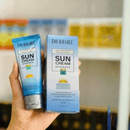Hand holding DR.RASHEL Sun Cream Hydrate SPF 50 tube and box together, showcasing sunscreen for UV protection and hydration in a real-life setting with blurred background