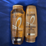 L’Oréal Elvive Extraordinary Oil nourishing shampoo and conditioner bottles placed side by side on a fabric surface, designed to provide deep nourishment and shine for dry hair