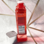 L’Oréal Revitalift 5% Pure Glycolic Acid peeling toner bottle placed on a marble surface with geometric golden background, showcasing a premium exfoliating skincare product for brighter and smoother skin
